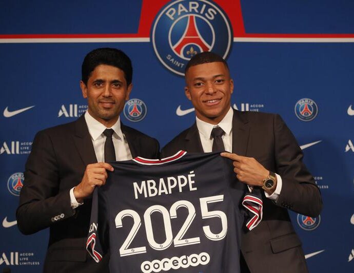 Kylian Mbappé (derecha) posa con su camiseta del Paris Saint-Germain junto al presidente Nasser Al-Khelaifi durante una rueda de prensa, el lunes 23 de mayo de 2022. (AP Foto/Michel Spingler)