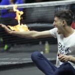 Un hombre se prende fuego en un brazo durante su protesta en el partido entre Diego Schwartzman y Stefanos Tsitsipas, en el evento de tenis Copa Laver en Londres, el viernes 23 de septiembre de 2022. (AP Foto/Kin Cheung)